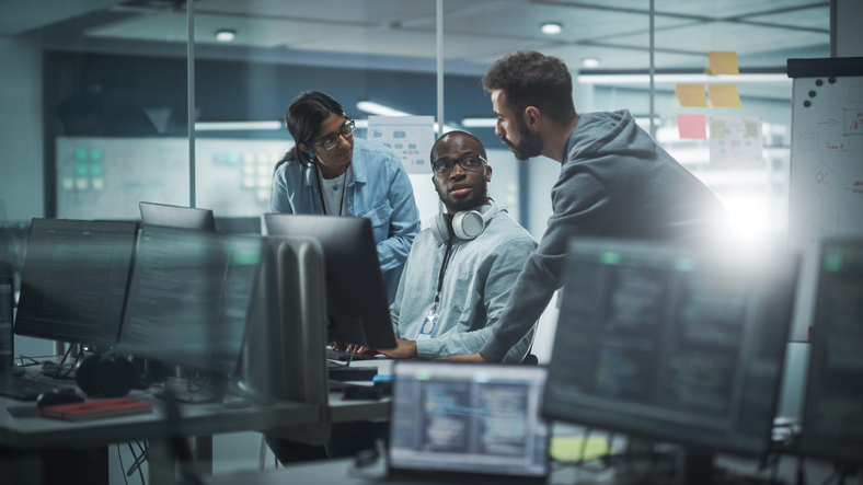 A diverse group of professionals brainstorming around a computer.