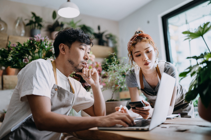 Small business owner couple in their shop focusing on a laptop.